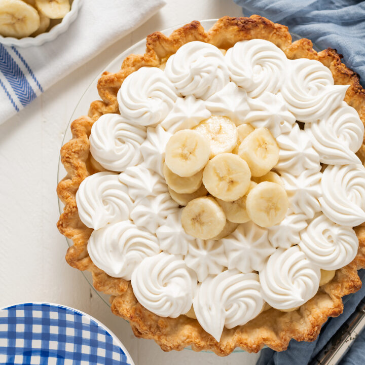 Overhead shot of Banana Cream Pie with blue gingham plates and blue towel.