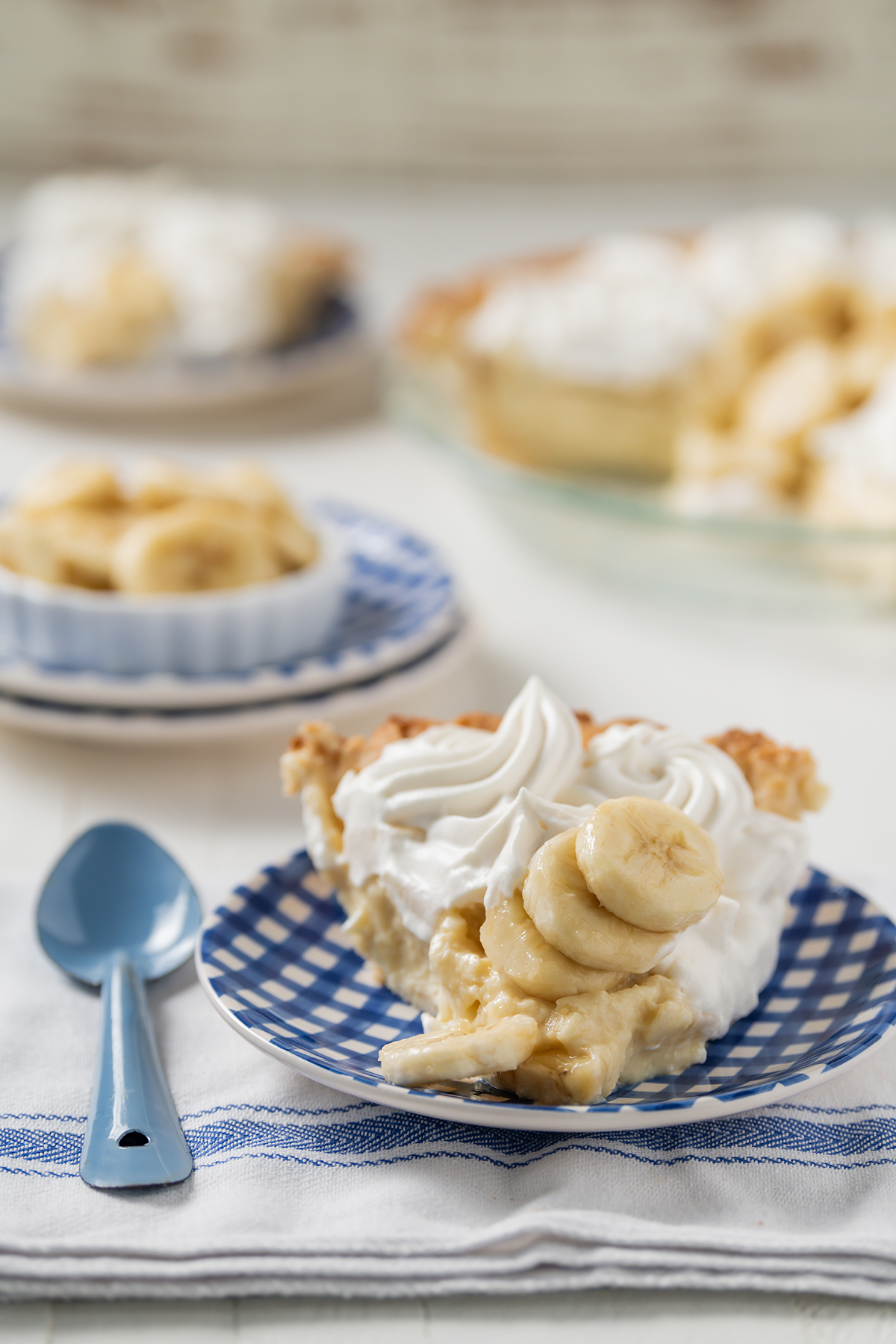 Close up shot of sliced Banana Cream Pie with blue spoon next to it.