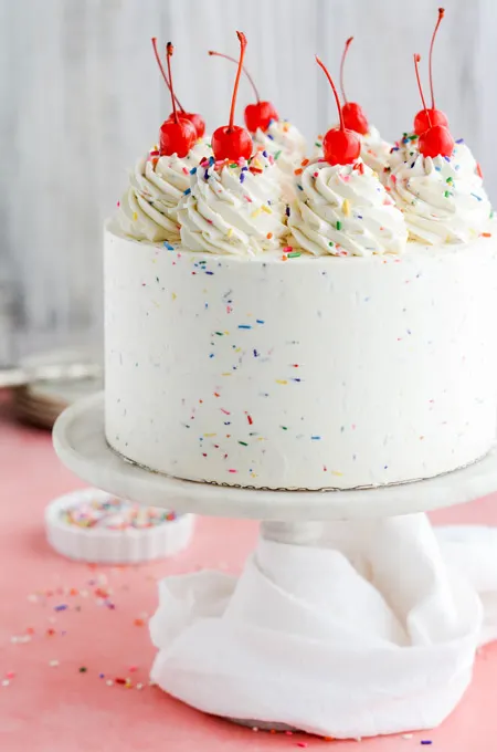 Charlotte Eclair Birthday Cake Garnished With Fresh Flowers, Waffle  Butterflies And Gold Topper, Tied With A White Ribbon, On White Background.  Stock Photo, Picture and Royalty Free Image. Image 174667061.