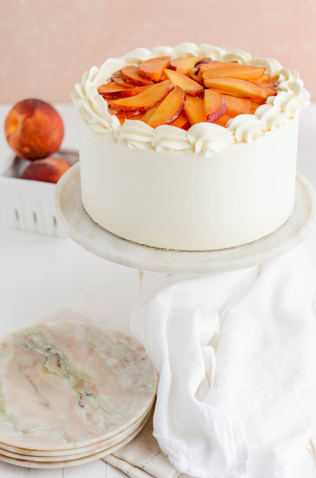 Peaches and Cream Layer Cake at a three-quarter angle on cake pedestal.