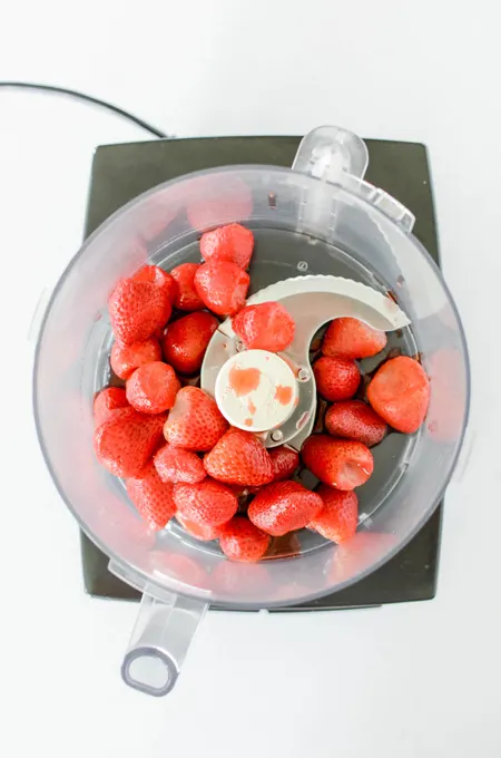 Strawberry Ice Cream Pop Cake overhead shot of thawed strawberries in food processor.