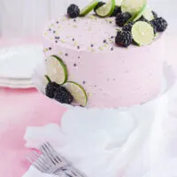 Lime Cake with Blackberry Filling cake on white cake pedestal.