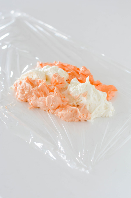 Orange Creamsicle Layer Cake colored frosting on plastic wrap.