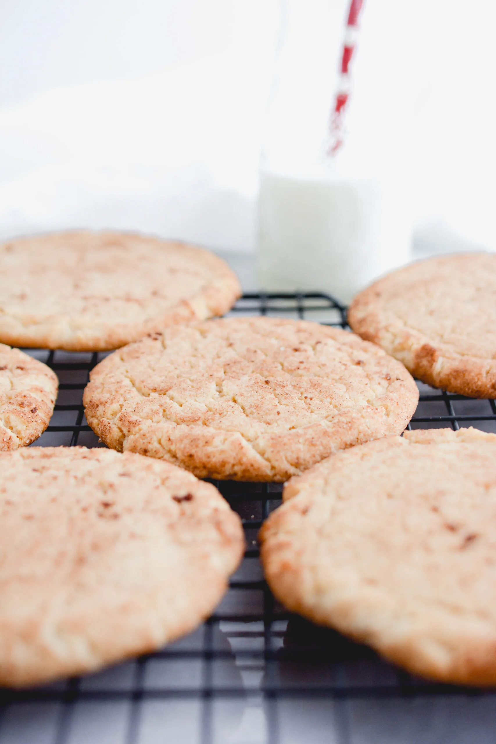 Close up of Snickerdoodle cookies on cooling rack with milk.