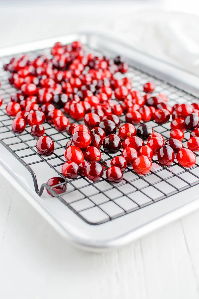 Cranberries covered in syrup on cooling rack for Orange Cranberry Cake.