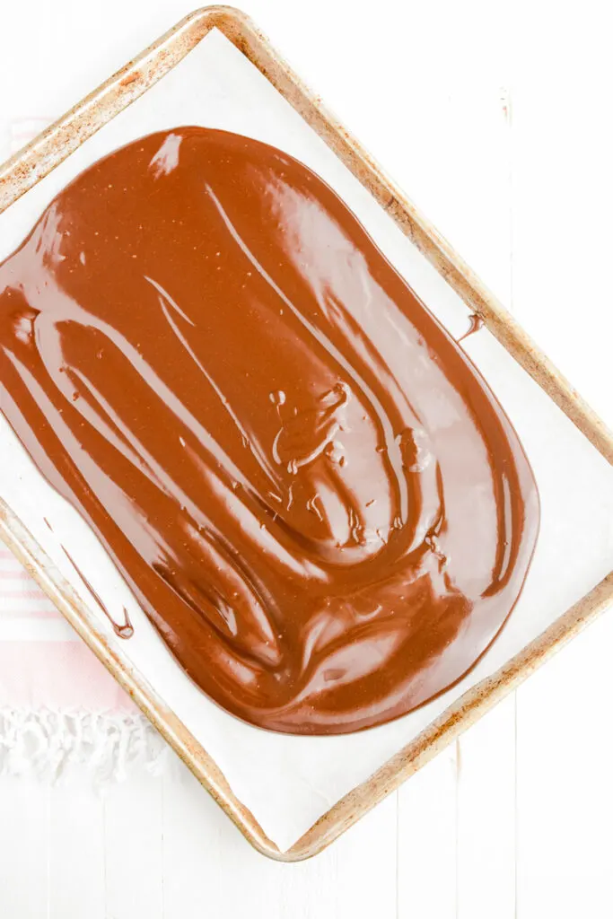 Overhead shot of chocolate spread out in a rimmed baking sheet for Strawberry Cinnamon Cake.
