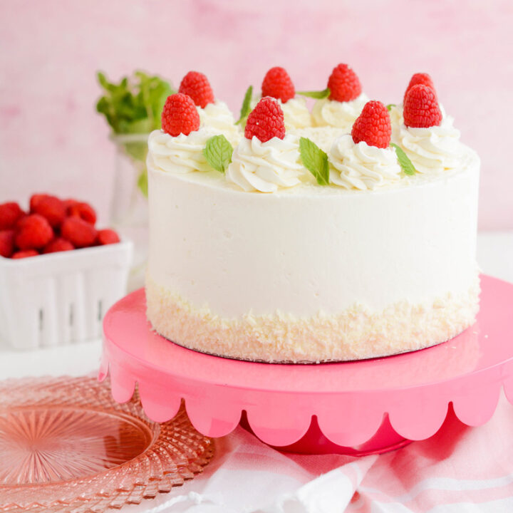 White Chocolate Raspberry Cake on pink cake pedestal.