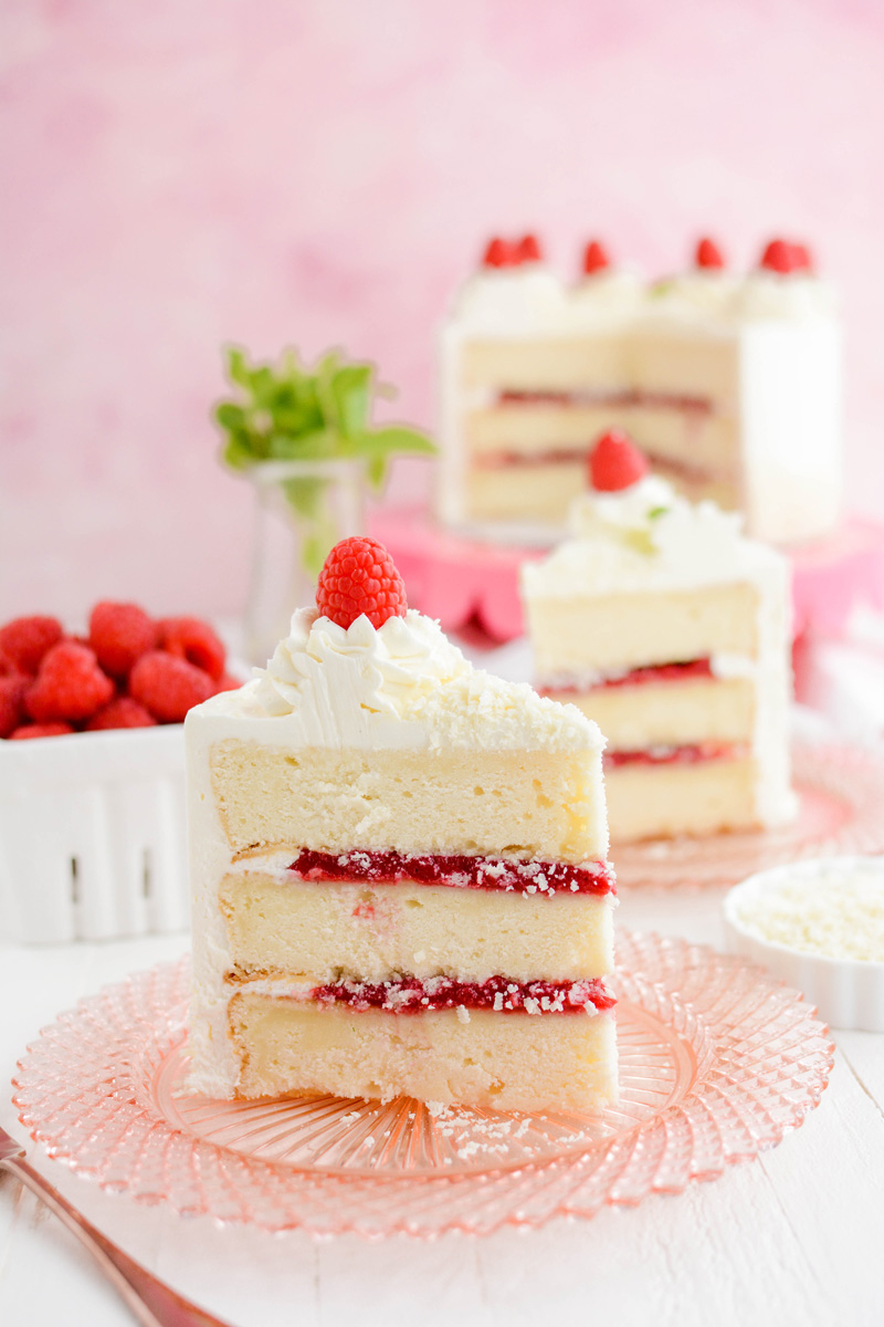 Wide open shot of cake slices on plates for White Chocolate Raspberry Cake.