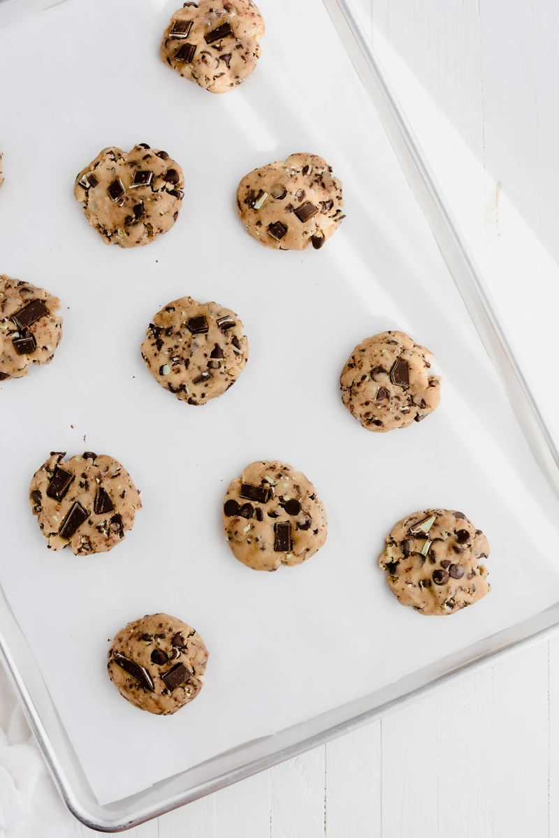 Overhead shot of cookie dough balls on lined baking sheet for Andes Mint Chocolate Chip Cookies.