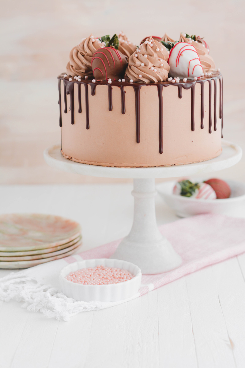 Wide open shot of Chocolate Covered Strawberries Cake on marble cake pedestal.