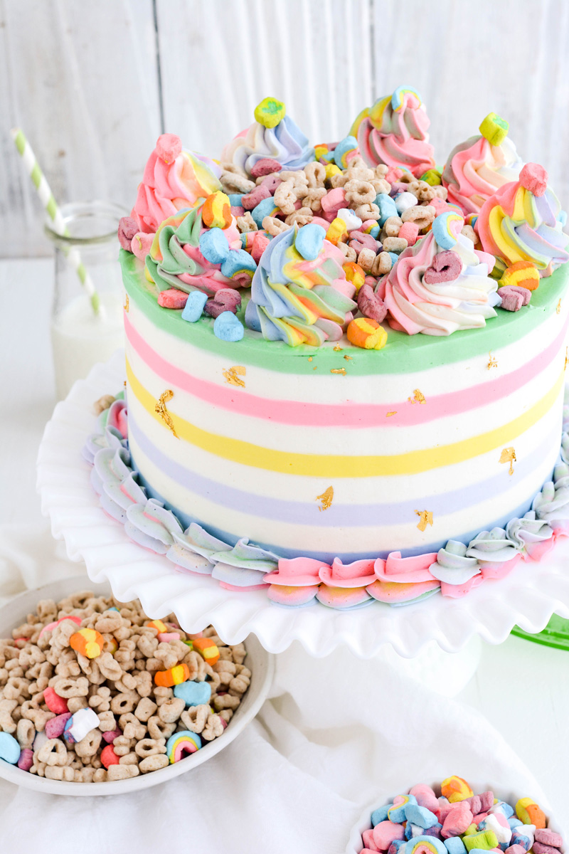 Three quarter angle of Lucky Charms Layer Cake on white cake pedestal.