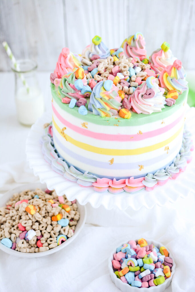 Three quarter angle of Lucky Charms Layer Cake on white cake pedestal.