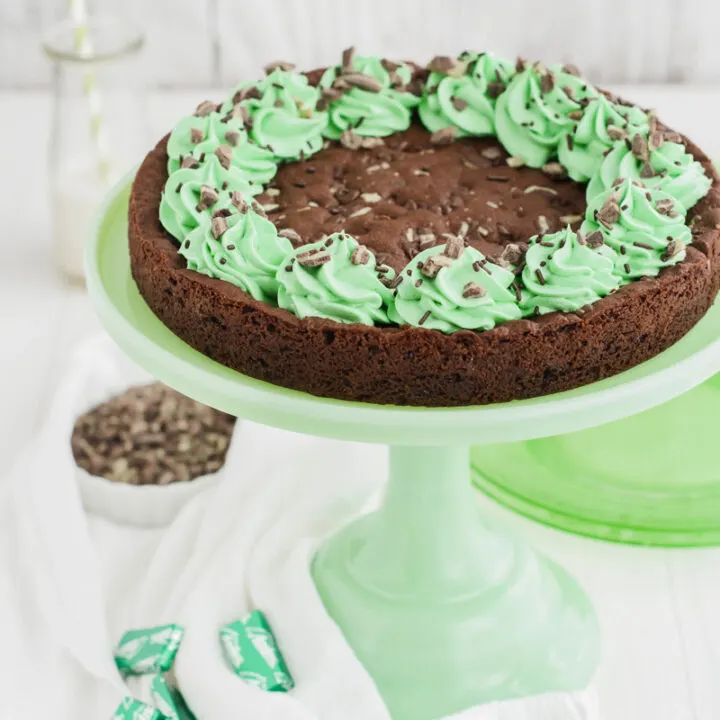 Close up three quarter angle shot of Mint Chocolate Chip Cookie Cake on green cake pedestal.