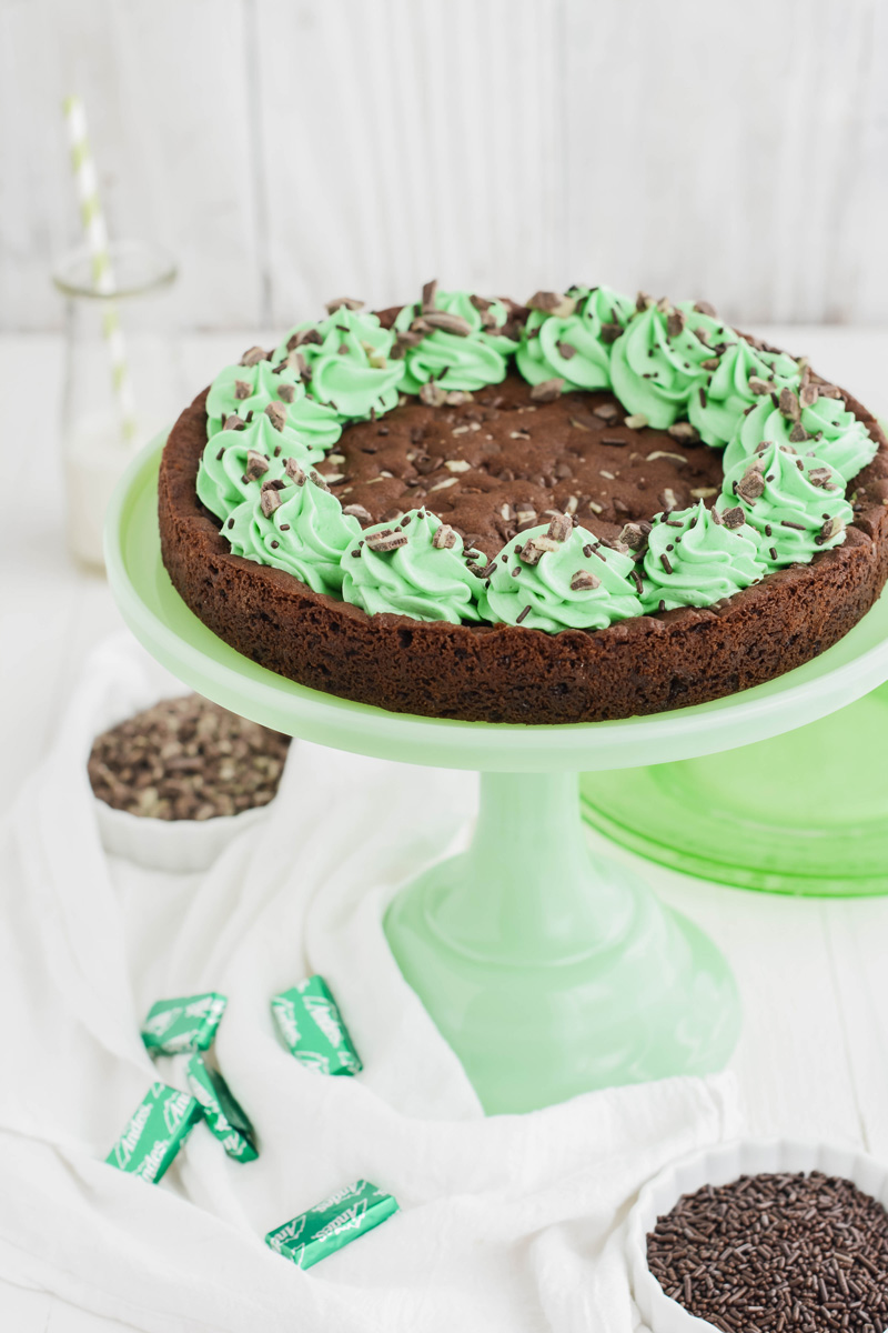 Close up three quarter angle shot of Mint Chocolate Chip Cookie Cake on green cake pedestal.