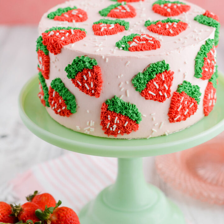 Strawberry Patch Layer Cake at a three quarter angle on green cake pedestal.