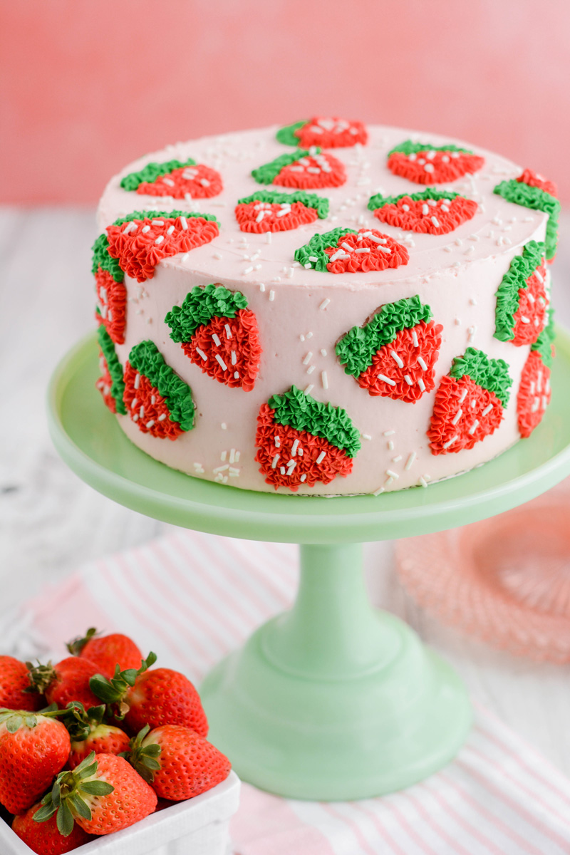Strawberry Patch Layer Cake at a three quarter angle on green cake pedestal.