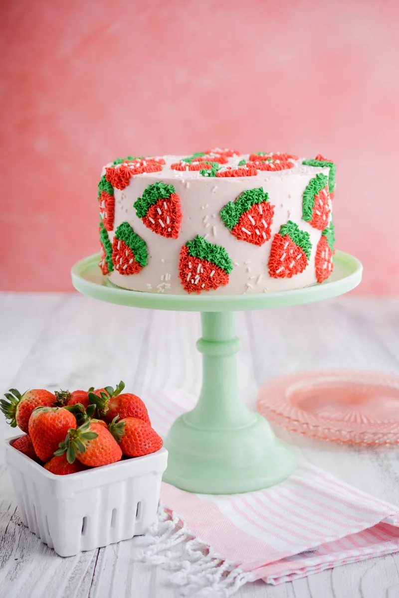 Wide open shot of Strawberry Patch Layer Cake on green cake pedestal.