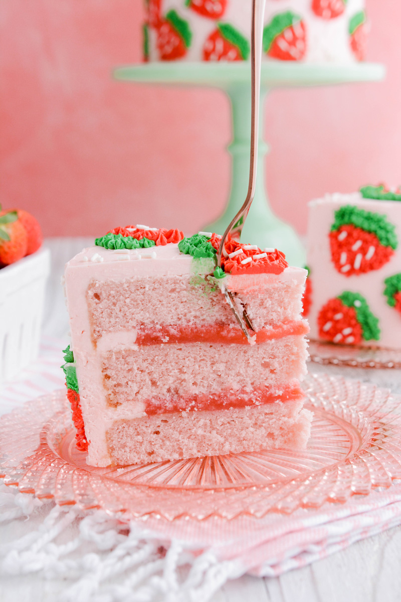 Close up of Strawberry Patch Layer Cake sliced with a fork on top.