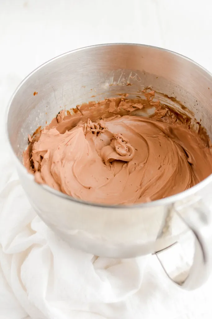 Three quarter angle of whipped ganache in mixing bowl for Chocolate Mint Cookie Layer Cake.