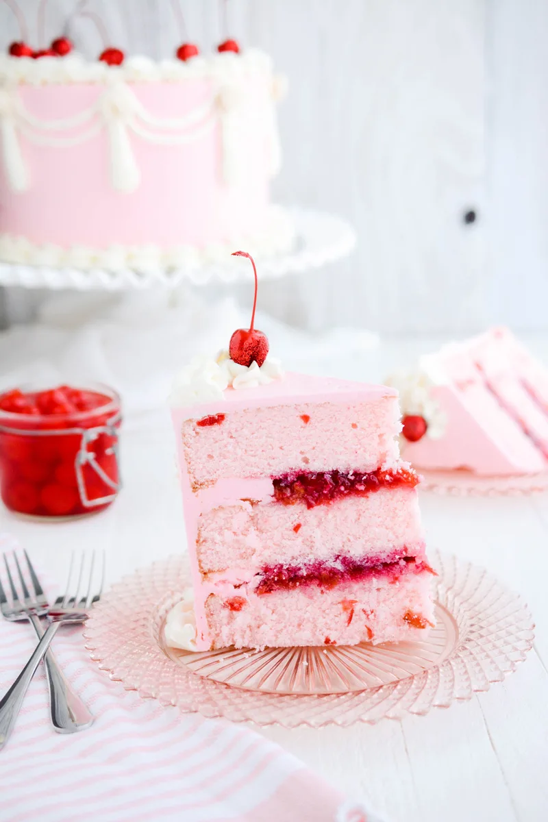 Close up shot of Vintage Cherry Layer cake sliced cake on pink plate. 