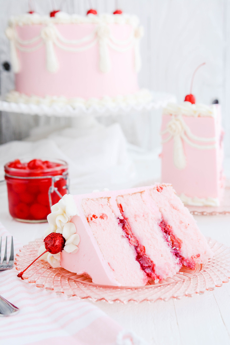 Close up of Vintage Cherry Layer Cake sliced on its side on a pink plate.