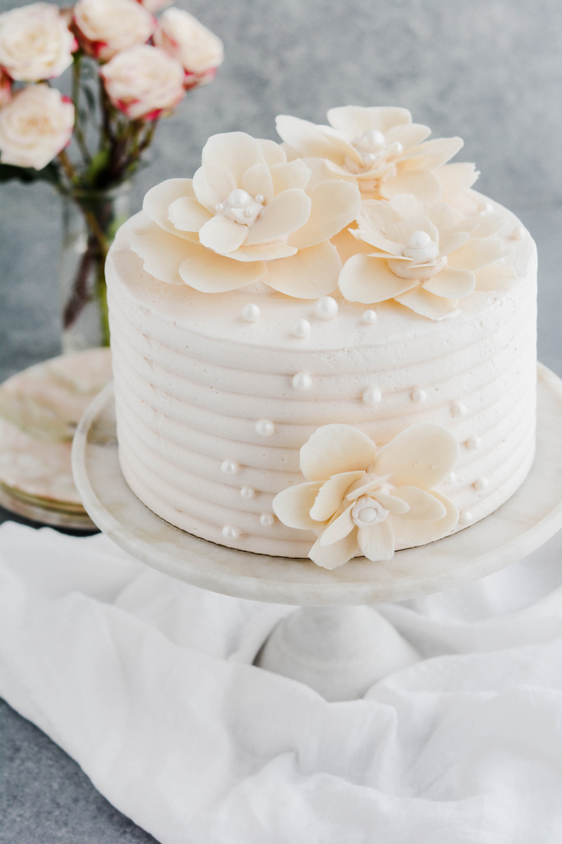 Three quarter angle White Chocolate Rose Cake on marble cake pedestal.