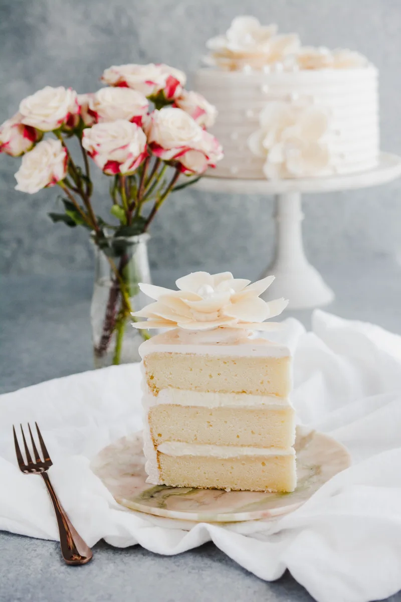 Wide open shot of sliced White Chocolate Rose Cake on marble plate.