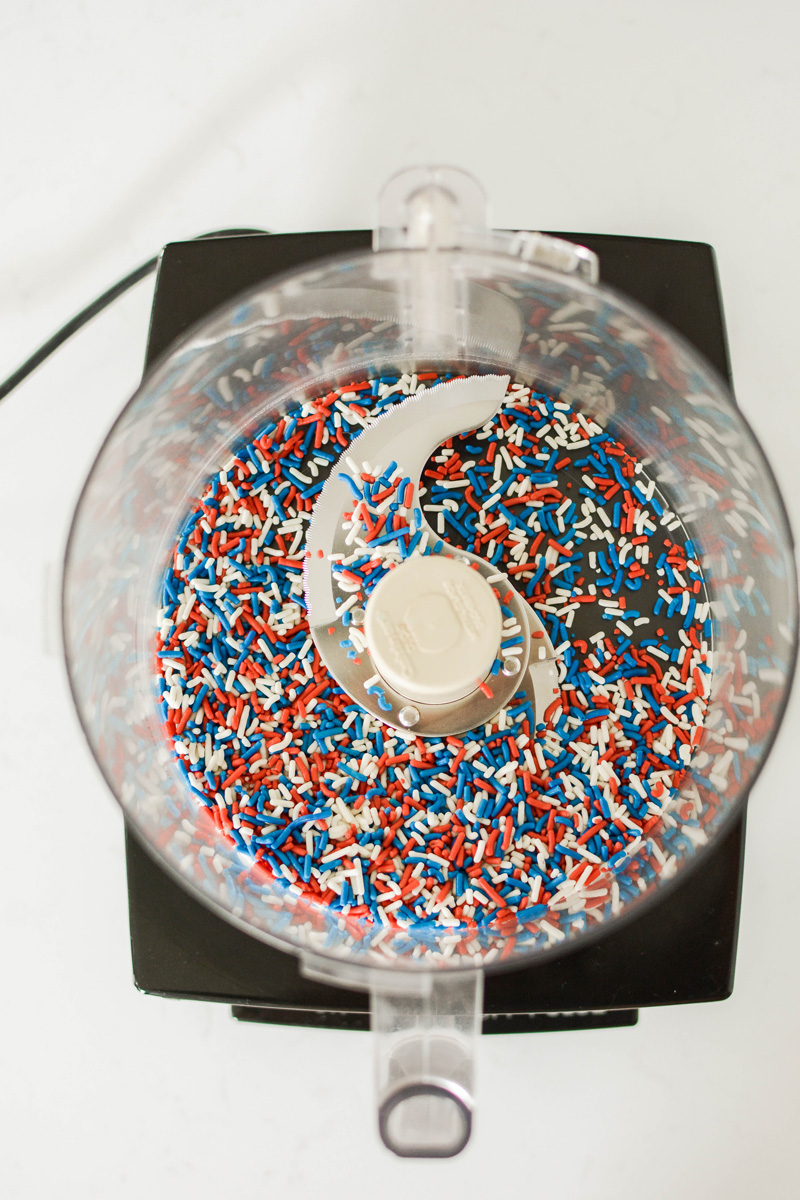 Overhead shot of unprocessed sprinkles in food processor for Patriotic Confetti Cupcakes.