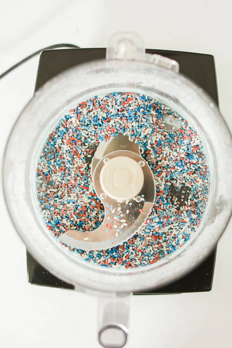 Overhead shot of processed sprinkles in food processor for Patriotic Confetti Cupcakes.