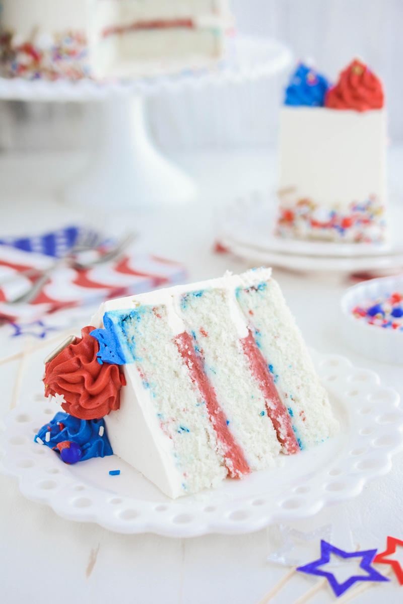 Sliced Patriotic Confetti Cake on its side on white plate.