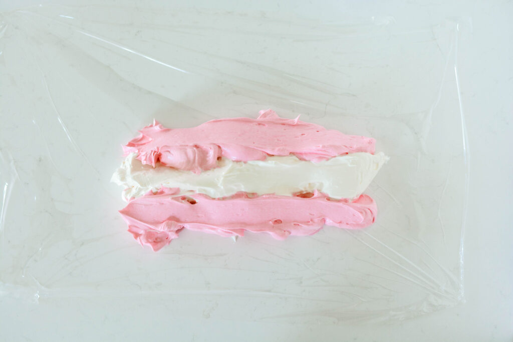 Overhead shot of pink and white buttercream on plastic wrap for Pink Bubble Gum Cupcakes.