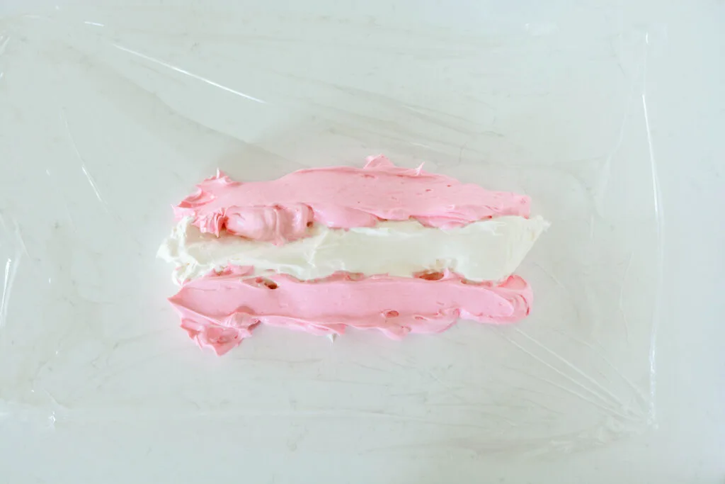 Overhead shot of pink and white buttercream on plastic wrap for Pink Bubble Gum Cupcakes.