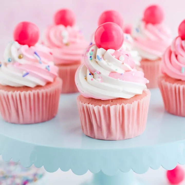 Close up of Pink Bubble Gum Cupcakes on teal cake pedestal.