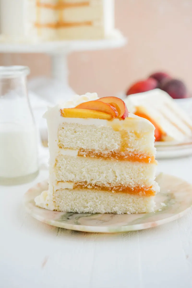 Close up shot of Peaches and Cream Layer Cake sliced on marble plate.