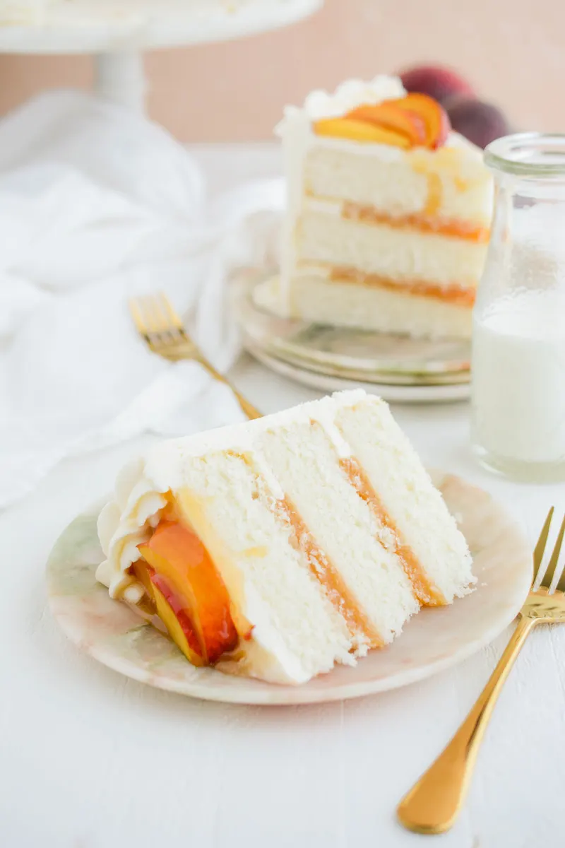 Close up shot of Peaches and Cream Layer Cake sliced on its side on marble plate.