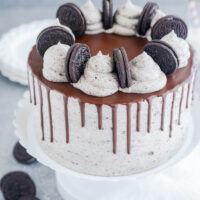 Ultimate Cookies and Cream Layer Cake at three quarter angle on white cake pedestal.