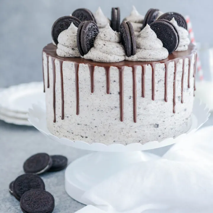 Ultimate Cookies and Cream Layer Cake on white cake pedestal.