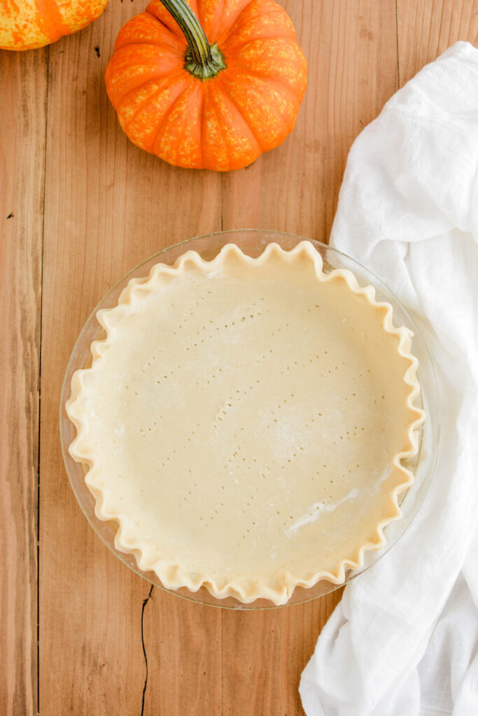 Overhead shot or raw pie dough in pie plate for Quintessential Pumpkin Pie.