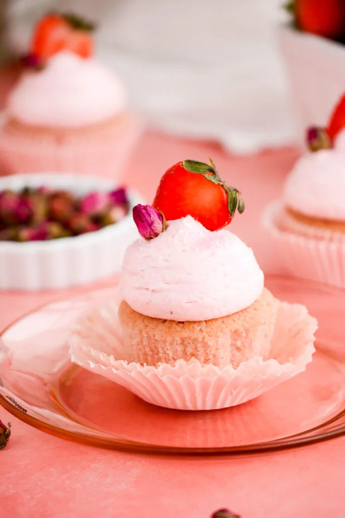 Close up of unwrapped Strawberry Rose Cupcake on pink plate.