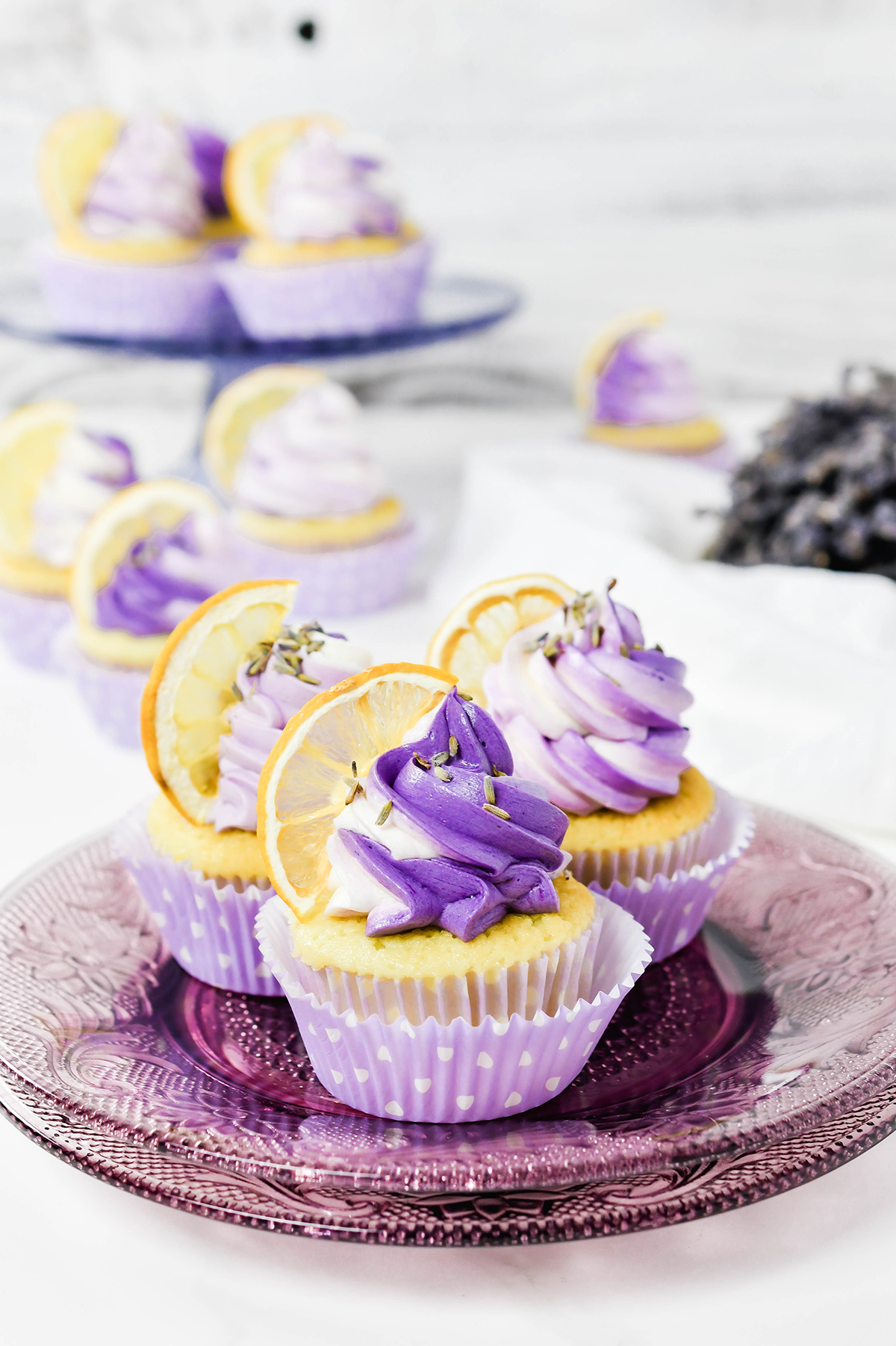 Three quarter angle of Lavender Lemon Cupcakes on a lavender plate.