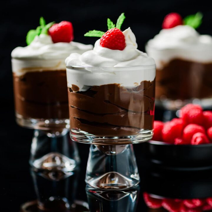Protein Packed Chocolate Mocha Pudding in parfait glasses with fresh raspberries and mint.