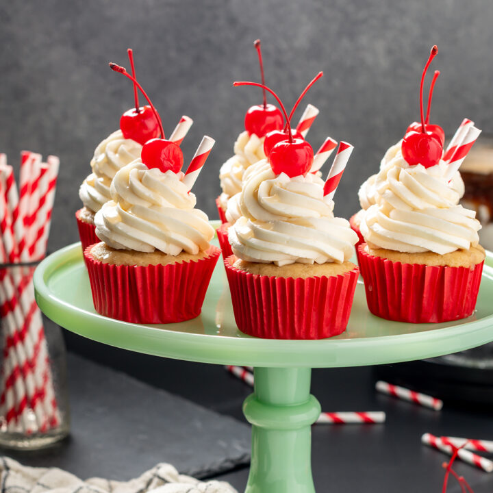 Head on shot of Root Beer Float Cupcakes on a green cake stand.