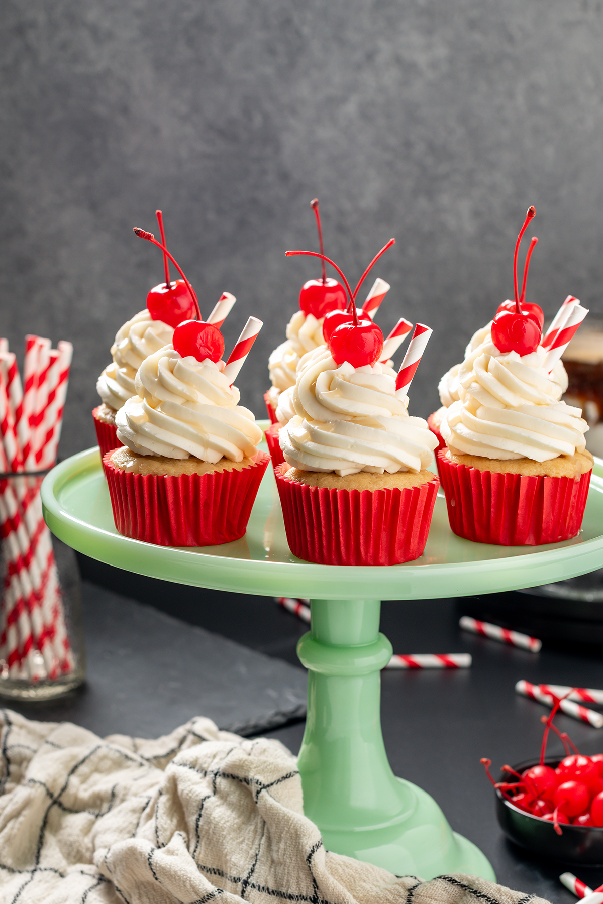 Head on shot of Root Beer Float Cupcakes on a green cake stand.