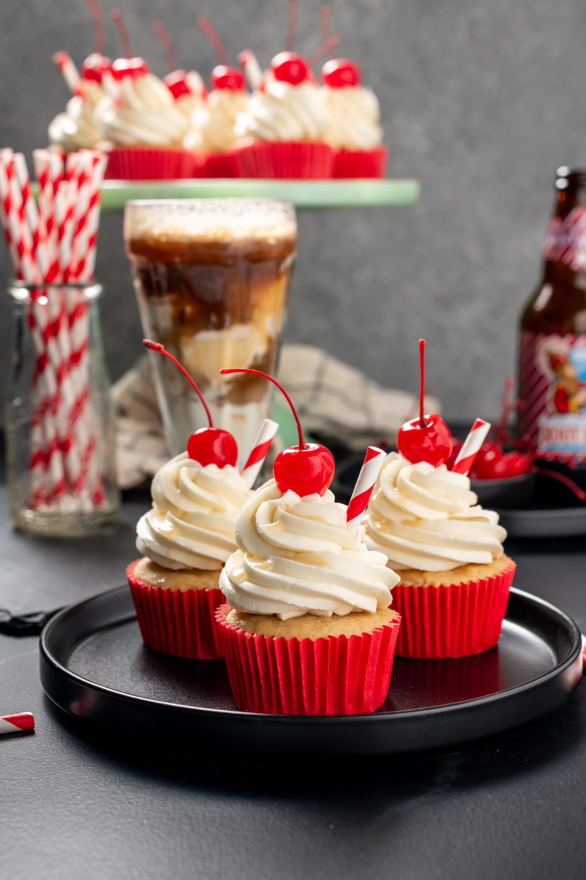 Three Root Beer Float Cupcakes on a black plate.