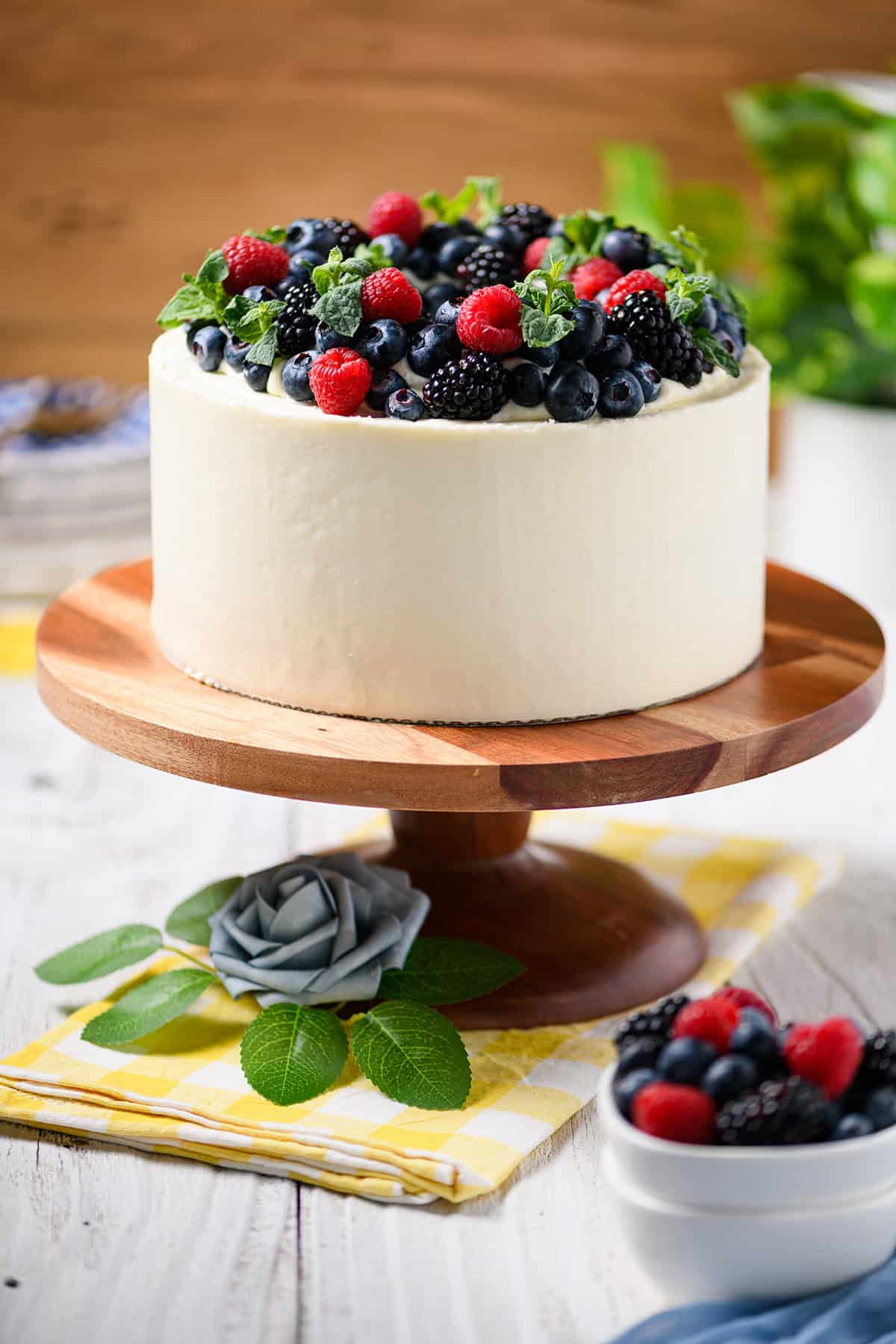 Straight on shot of Mixed Berries and Cream Cake on wood cake pedestal.
