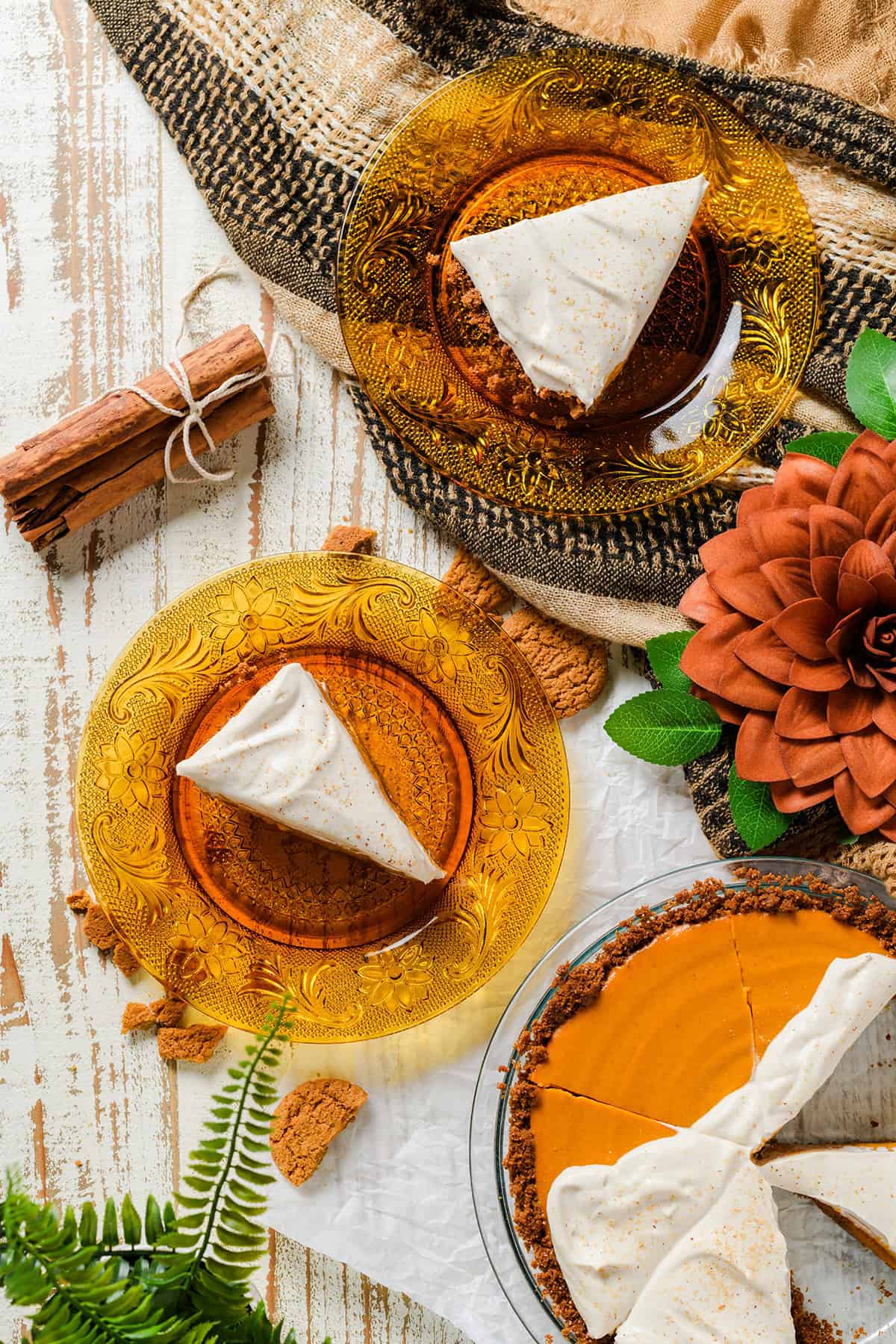 Overhead shot of sliced Pumpkin Pie with Gingersnap Crust and 2 slices of pie on orange antique plates.