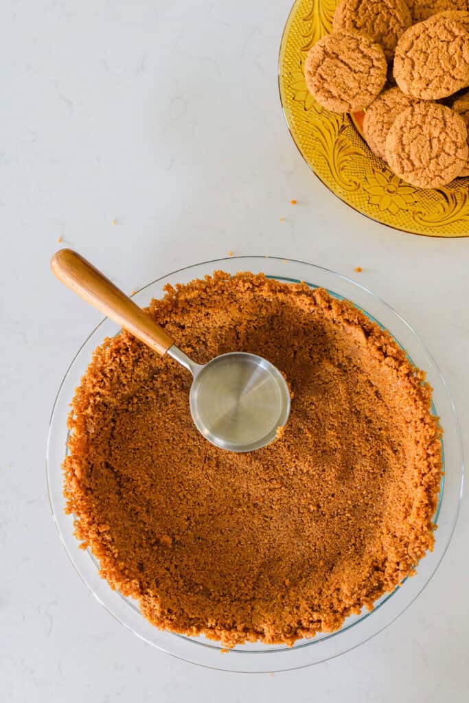 Overhead shot of gingersnap cookie crumbs pressed into pie plate.