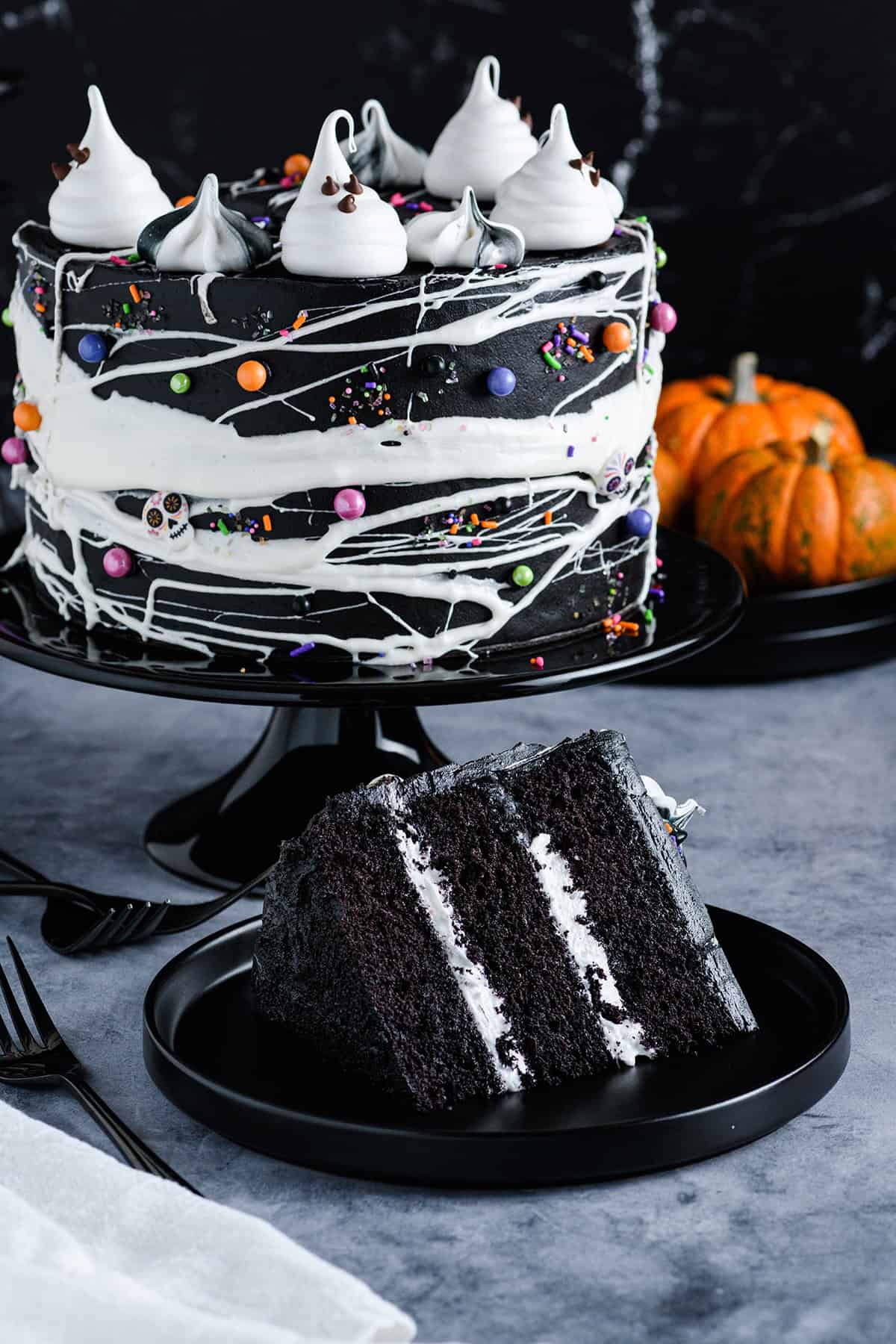 Three quarter angle of sliced cake on its side on black plate with Black Velvet Halloween Cake behind it.