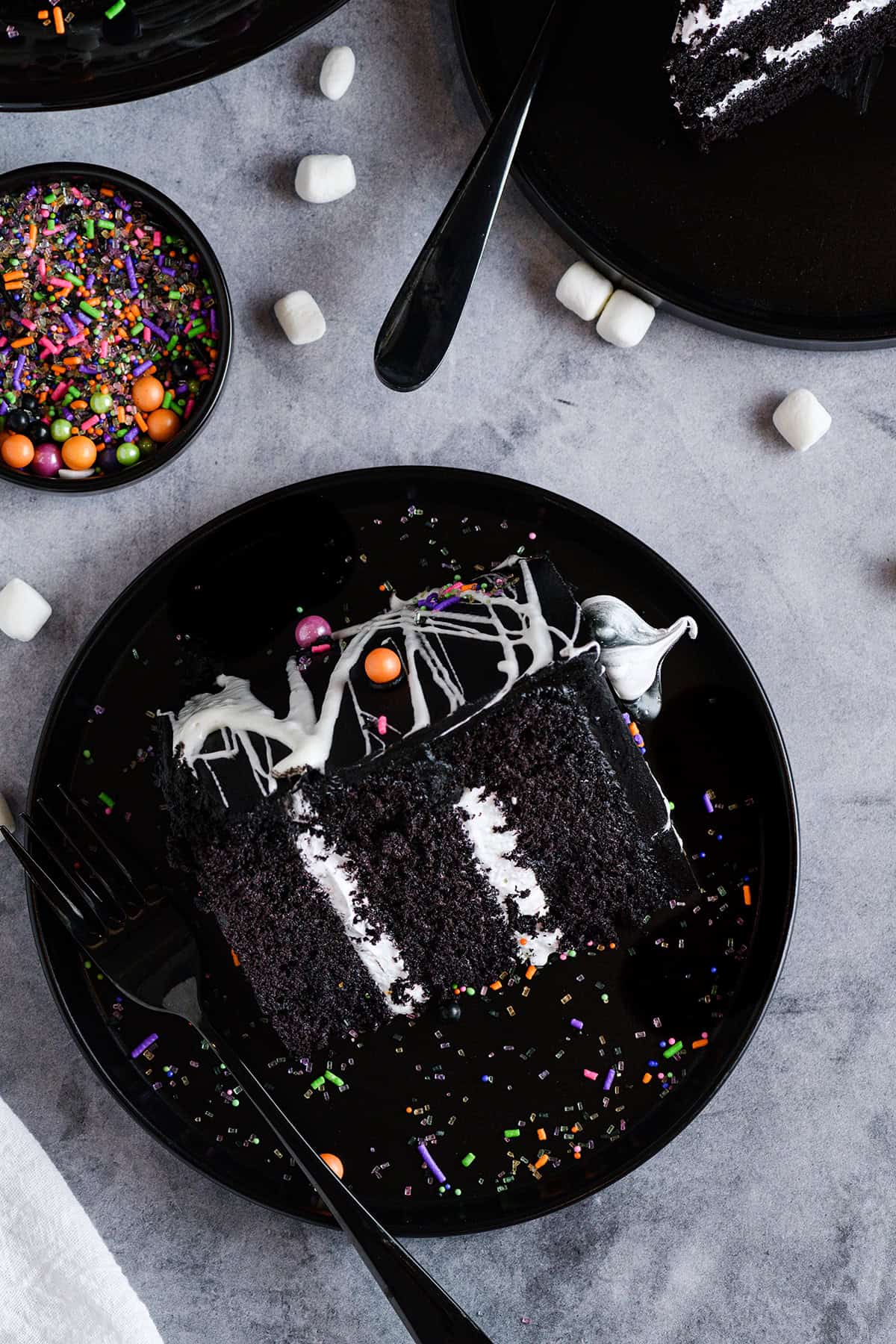 Overhead shot of sliced Black Velvet Halloween Cake on black plate.