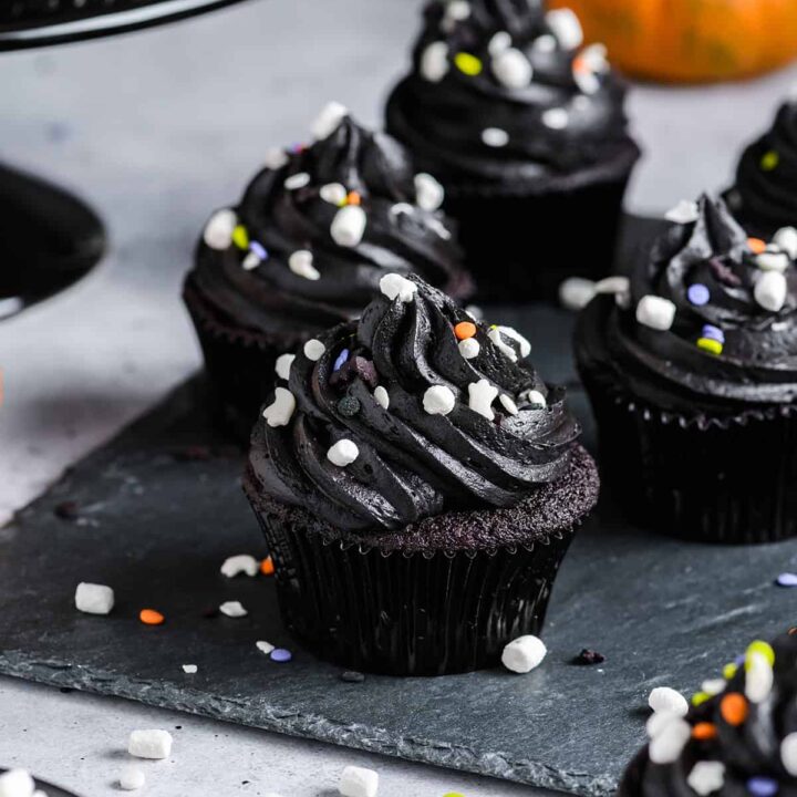 Three quarter angle of Black Velvet Halloween Cupcakes on slate serving plate.